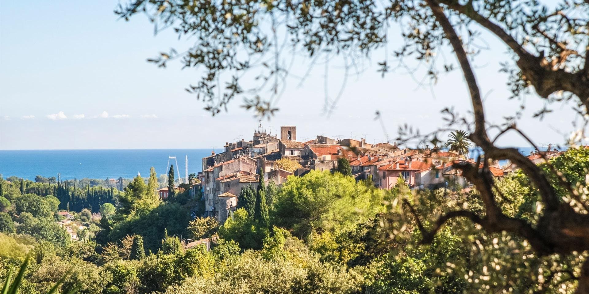 Aerial view of Biot medieval hilltop village with terracotta rooftops, stone ramparts, and cypress trees on the French Riviera hinterland