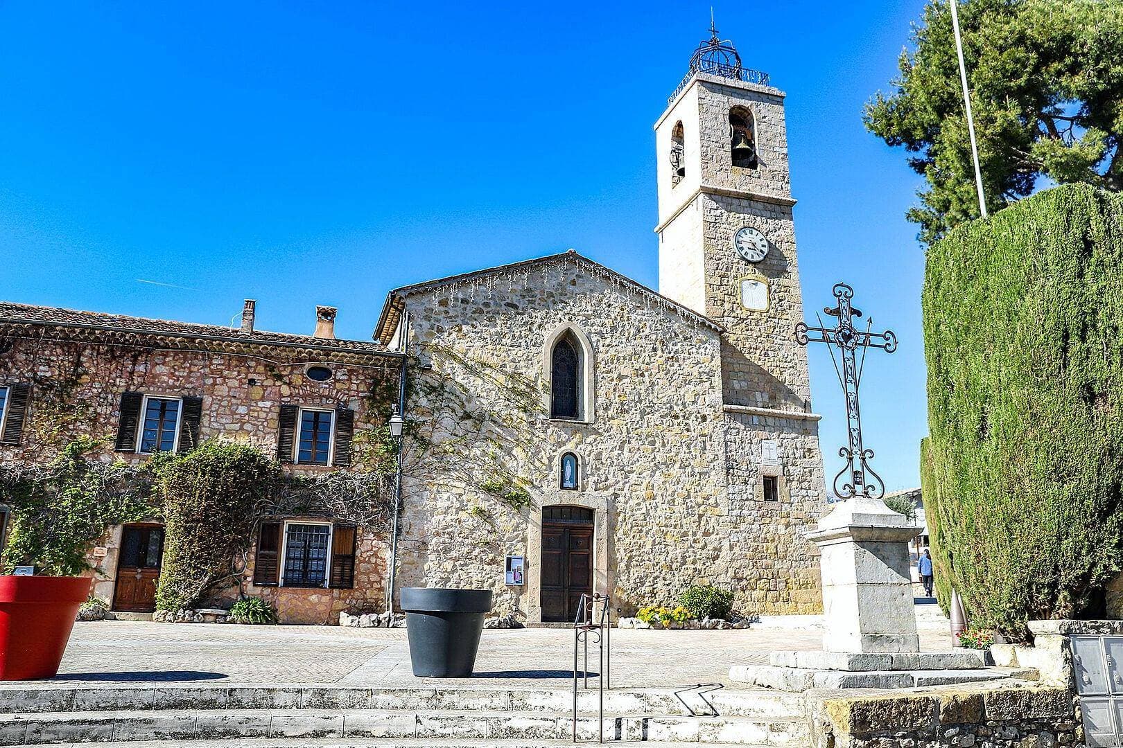 Charming Provençal village square with century-old plane trees, traditional stone buildings, and café terraces in Le Rouret, the Alpes-Maritimes truffle capital