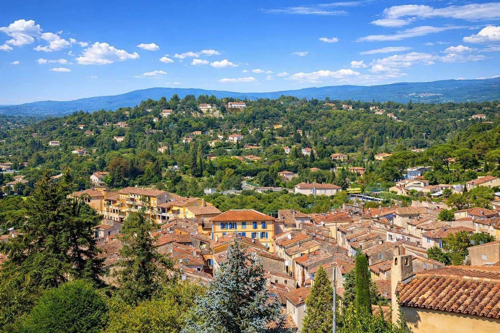 Panoramic aerial view of Valbonne village with terracotta rooftops, stone buildings, and cypress trees in the hills of the French Riviera hinterland