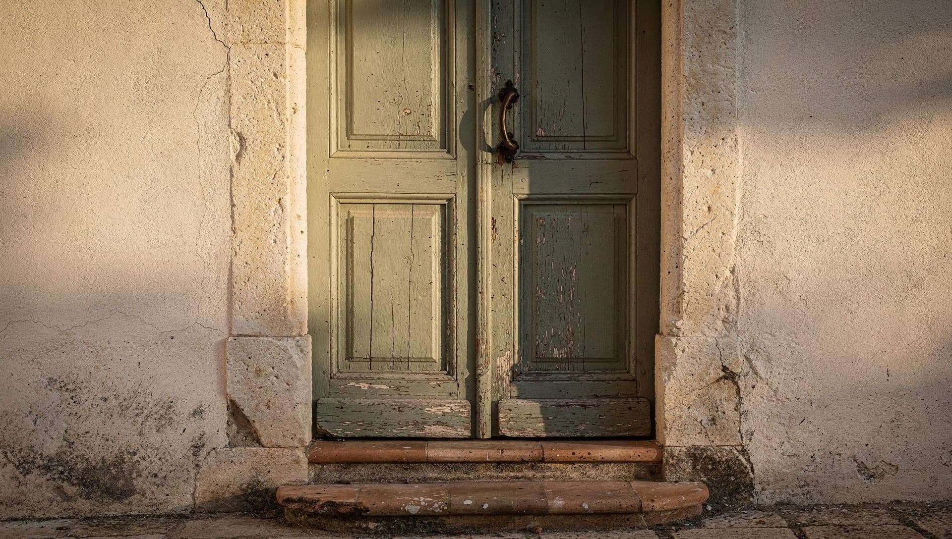 Weathered green timber door in a limestone surround in the old village of Valbonne at late afternoon