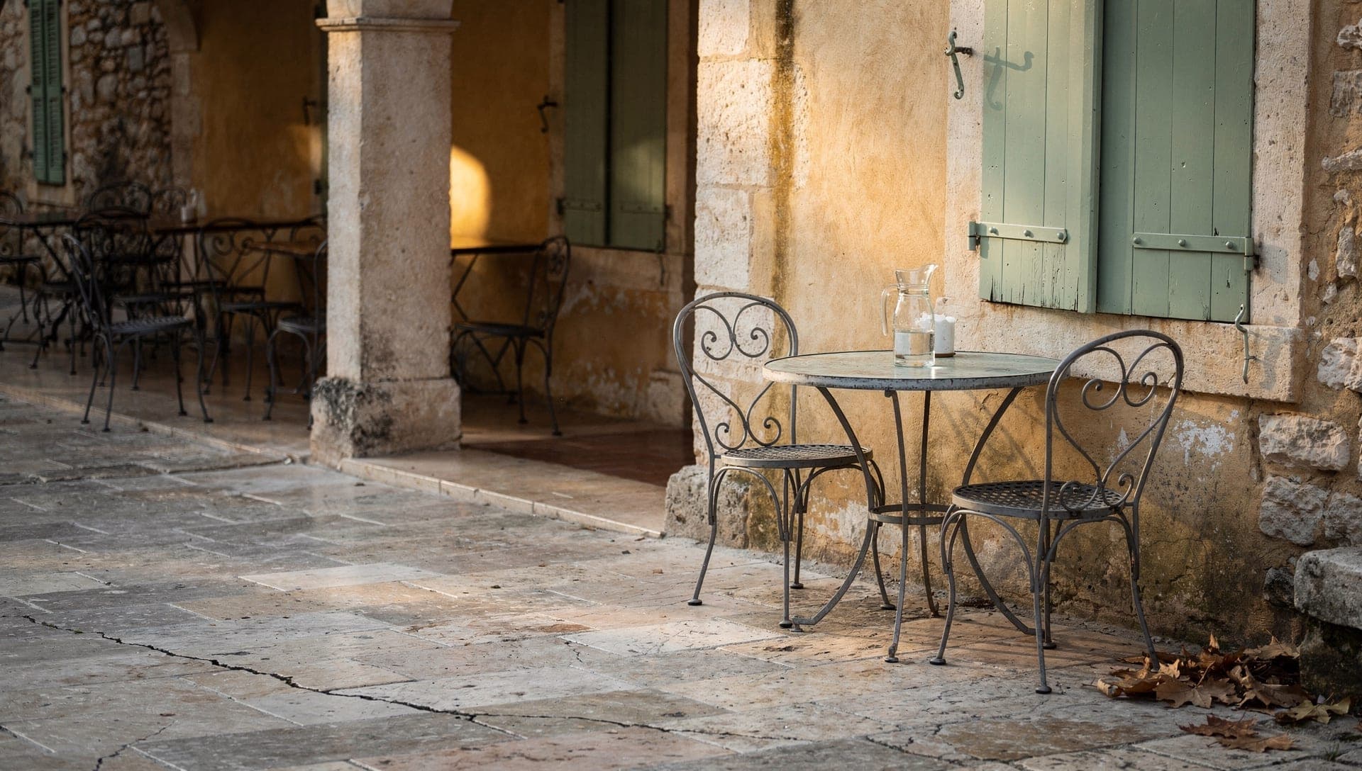 Tables de café vides sous les arcades en pierre de la place des Arcades du vieux village de Valbonne dans la lumière du matin