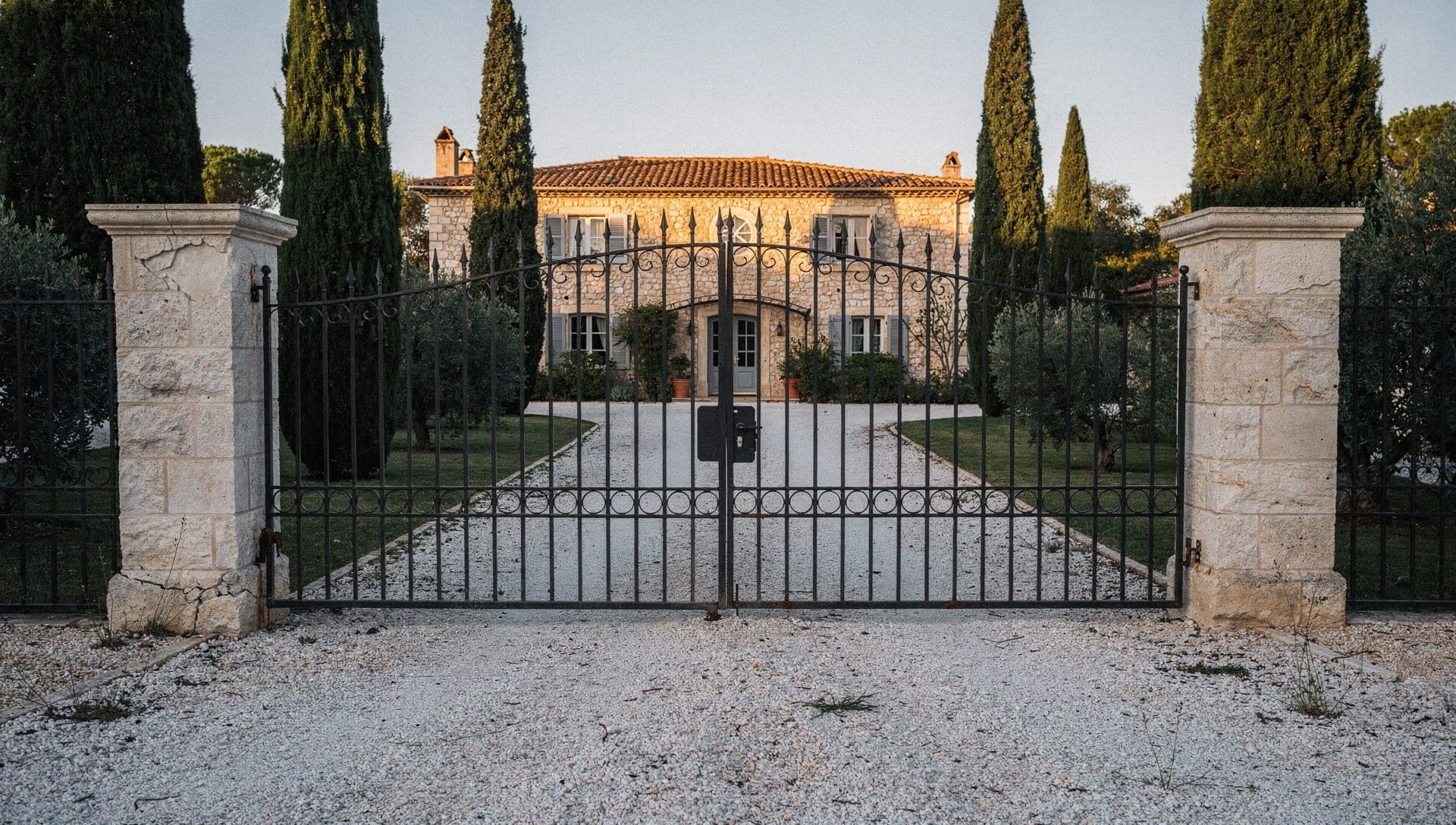 A stone Provencal family house in the Riviera hinterland standing closed up with every shutter shut and a rusted chain across the gravel drive, a jointly inherited property held in indivision